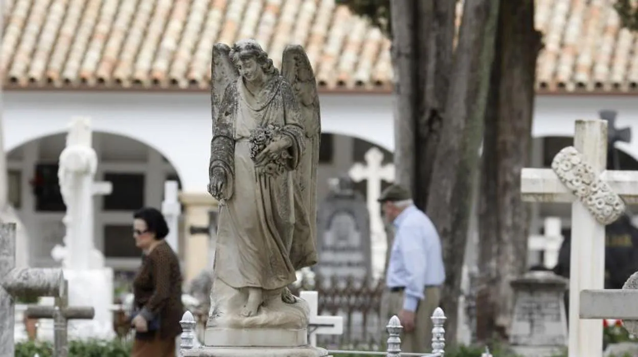 Dos personas pasan entre las lápidas del cementerio de San Rafael