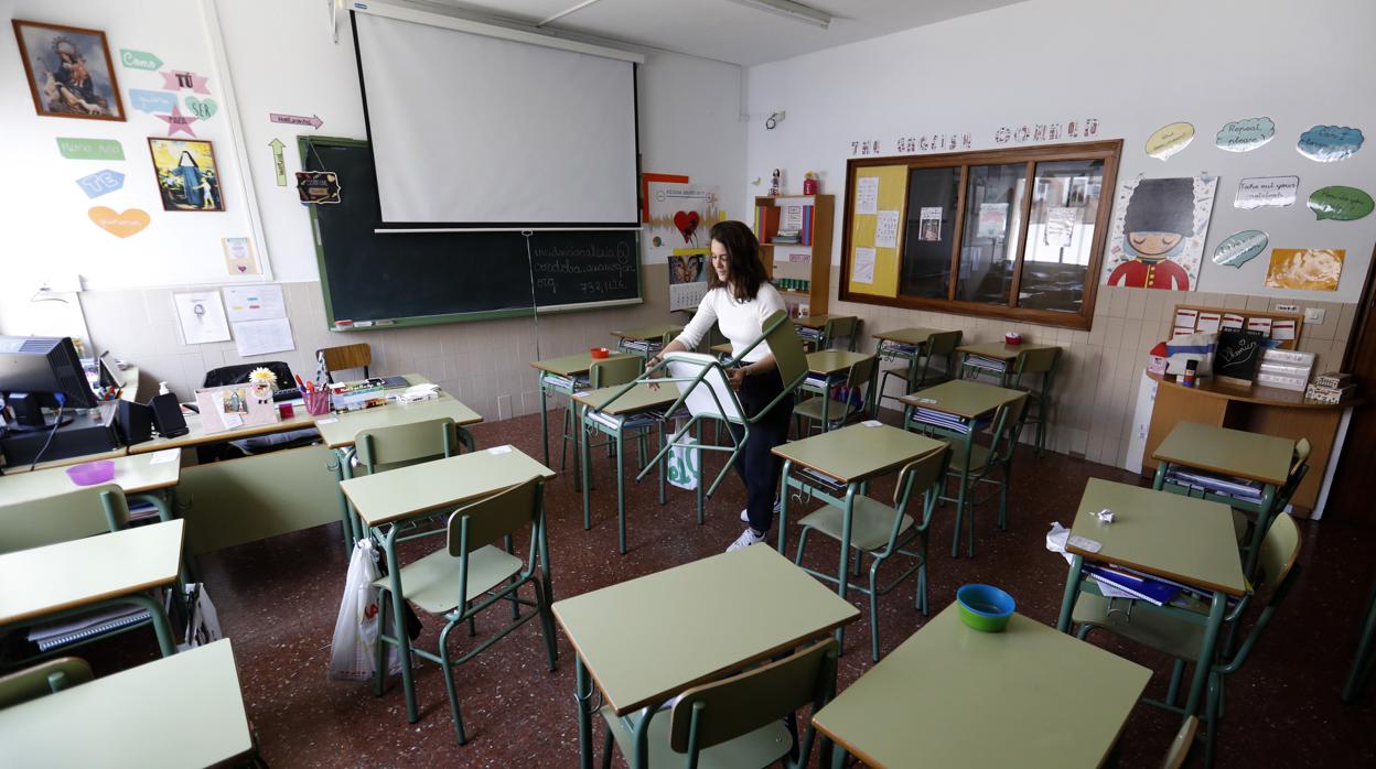 Una profesora recoge una silla tras el corte de las clases