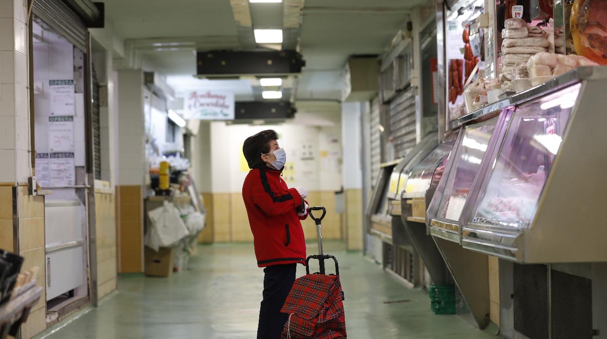 Una mujer con mascarilla hace su compra en un mercado municipal