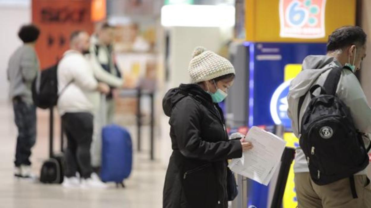 Dos personas hacen cola con mascarillas puestas