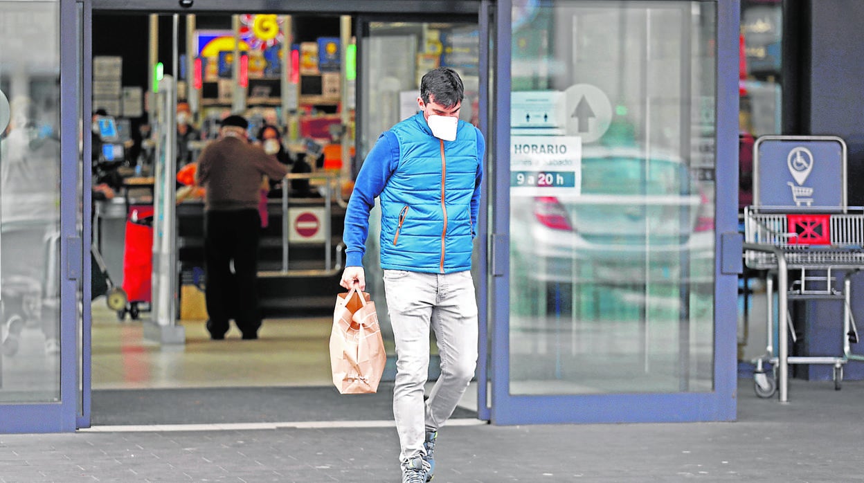 Un hombre sale de un supermercado con una bolsa de la compra