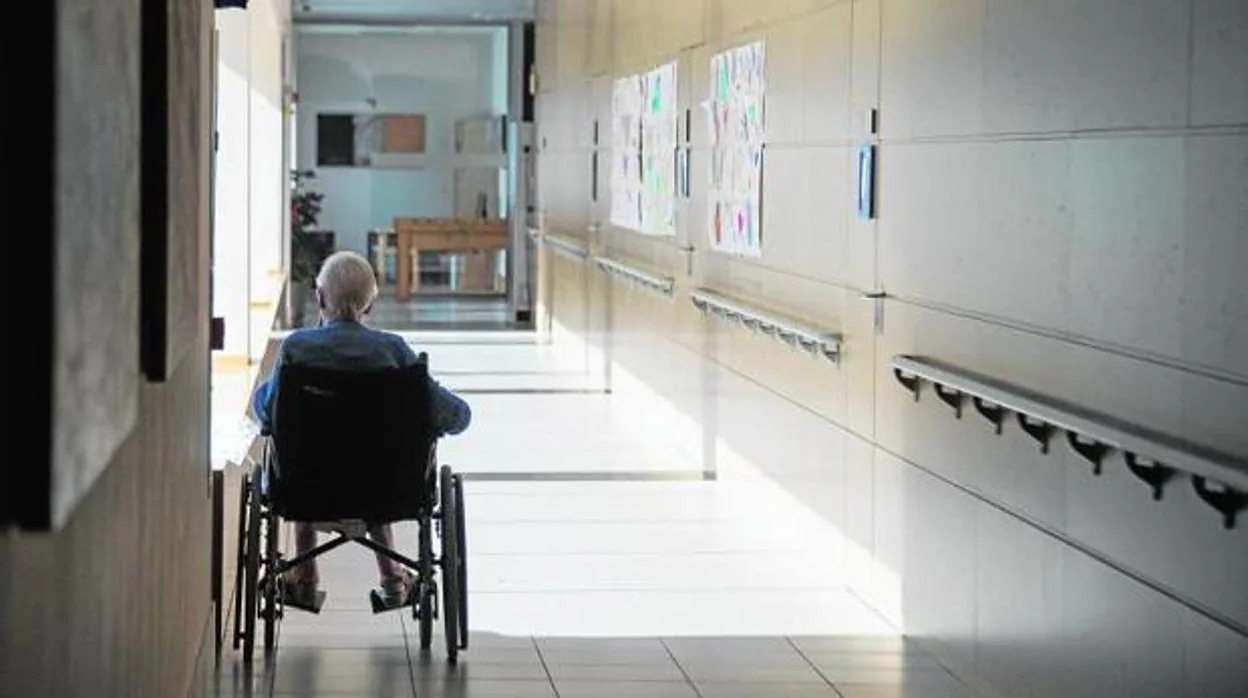 Una persona mayor en silla de ruedas en el pasillo de una residencia de Córdoba