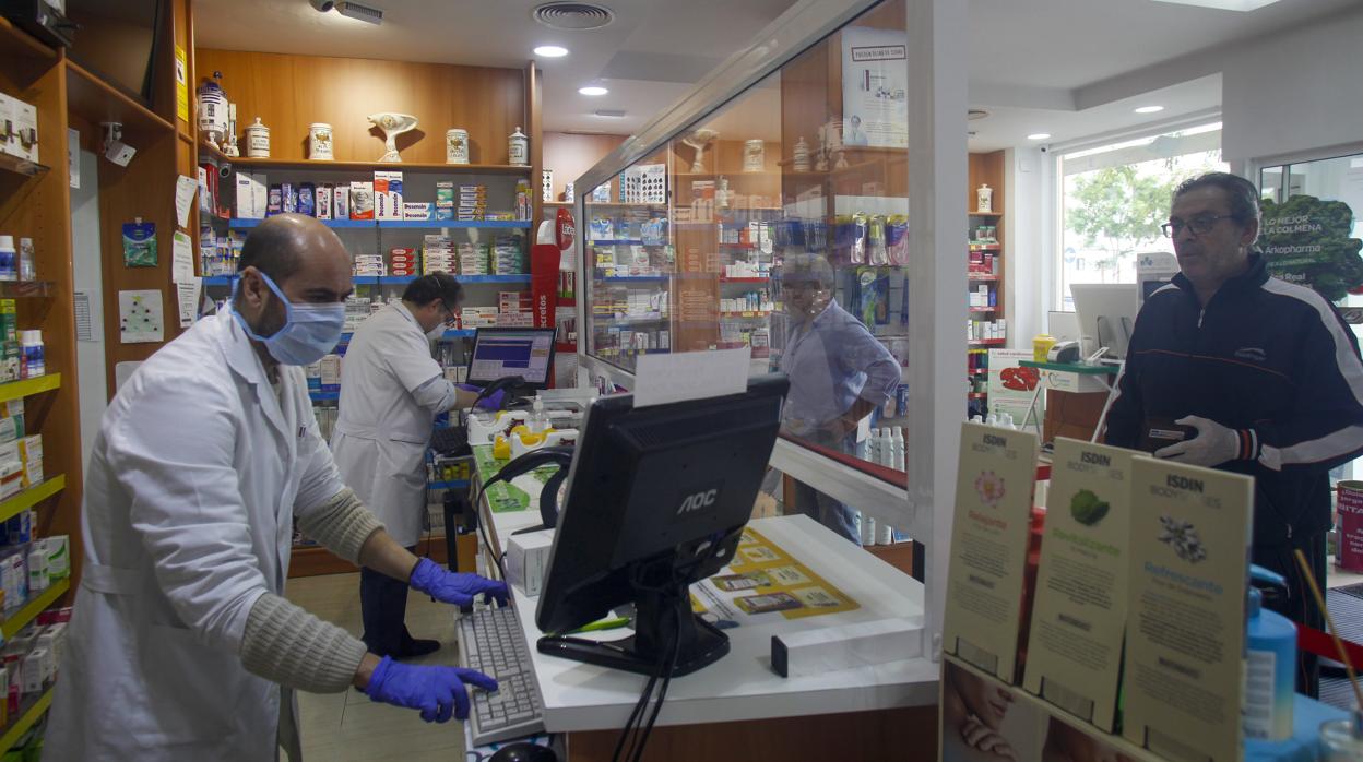 Una farmacia sevillana con su pantalla de metacrilato como protección contra el Covid-19