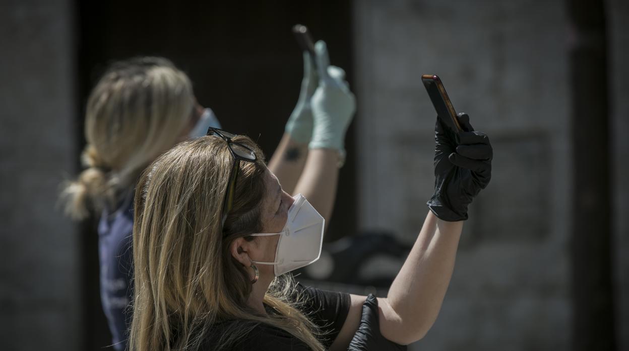 Estampa de dos muejres usando mascarillas en las calles de Sevilla