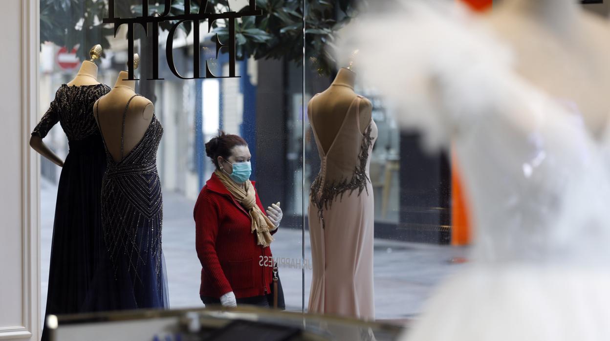 Una mujer pasa frente a un escaparate de uno de los comercios cerrados por el coronavirus