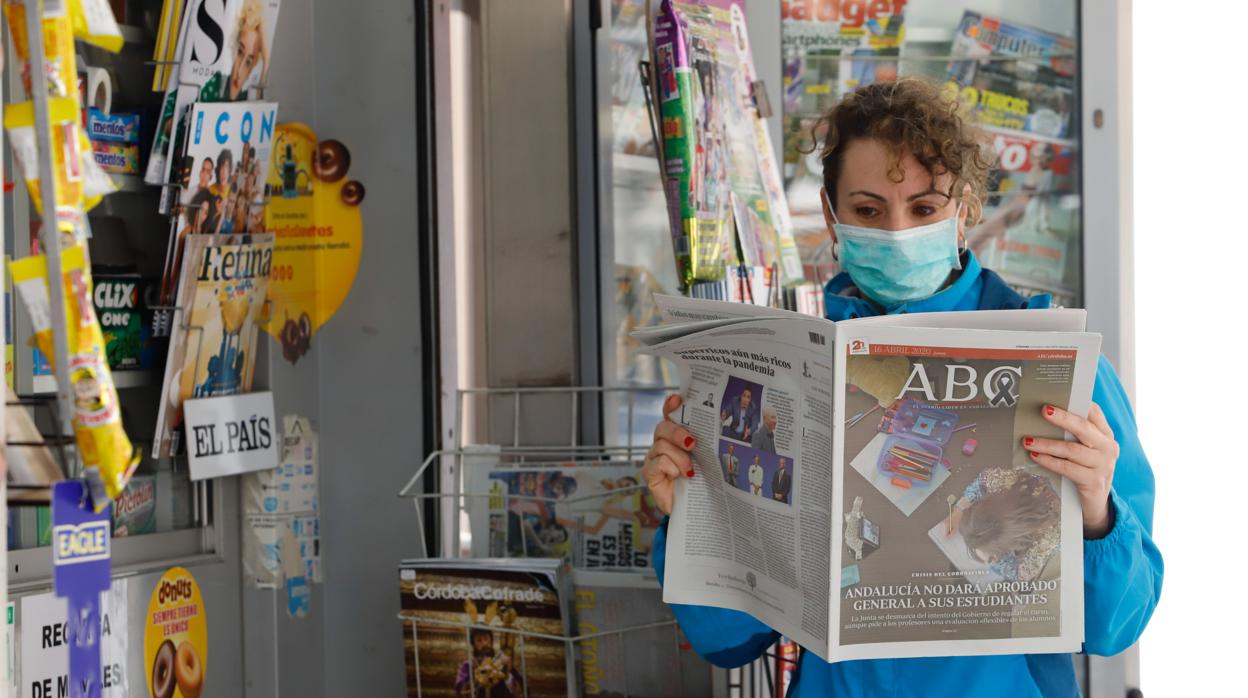 Una joven lee el periódico en un quiosco