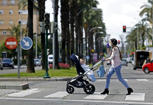 Una mujer cruza un paso de cebra con su bebé en la avenida de Manolete