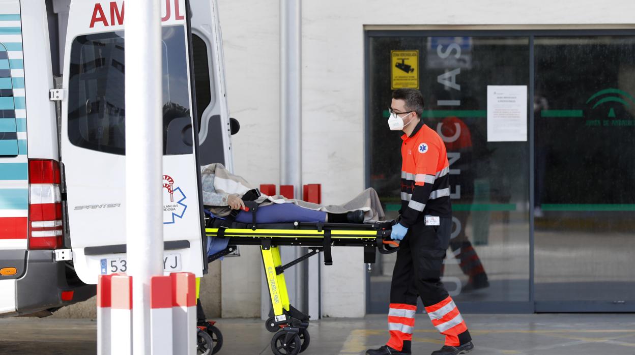 Un trabajador sanitario traslada a una paciente, en uno de los accesos del Reina Sofía de Córdoba