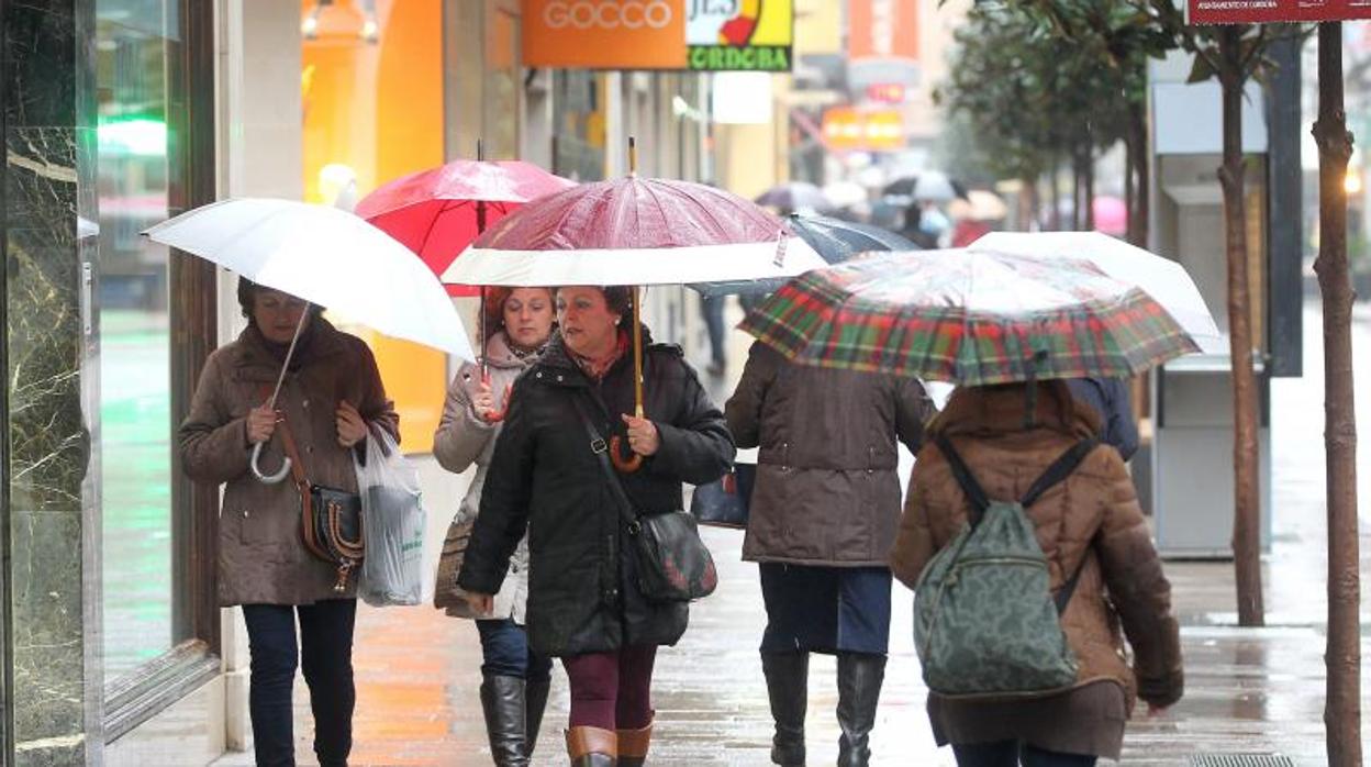 Personas con paraguas por una calle de Córdoba