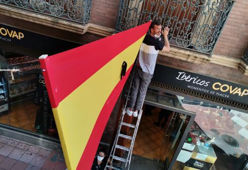 En bandera de España con un crespón de luto en la entrada a la calle