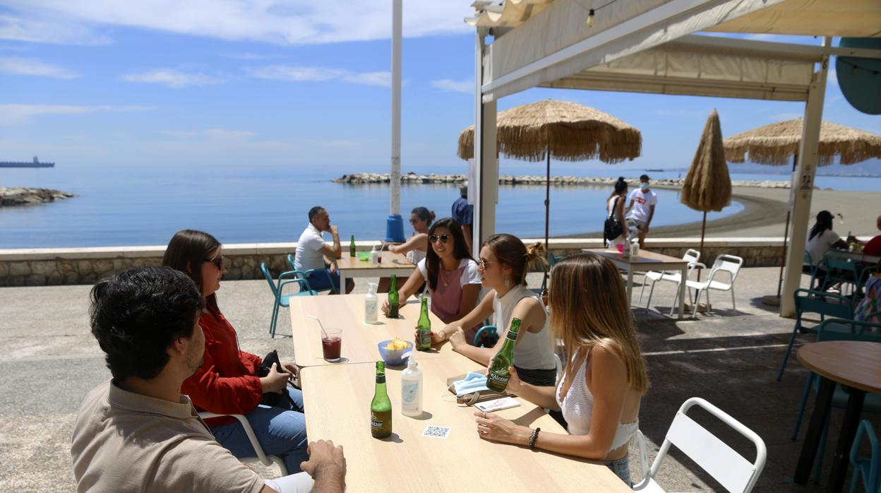 Un grupo de jóvenes en una terraza en el paseo marítimo de Pedregalejo en Málaga