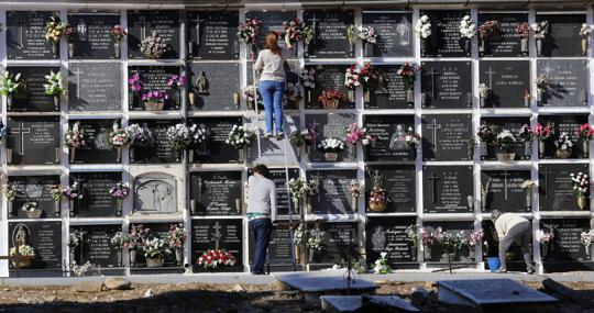 Famiiares de fallecidos colocan flores en los nichos