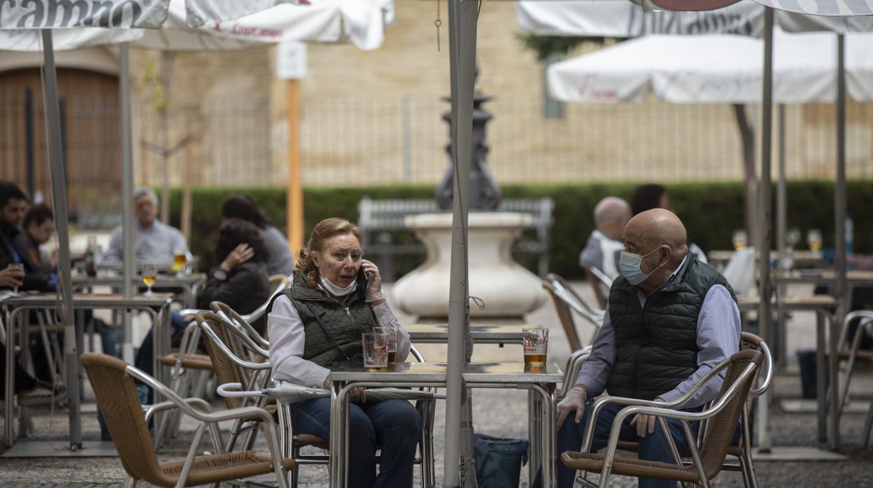 Una pareja sentada en un velador guardando todas las distancias de seguridad