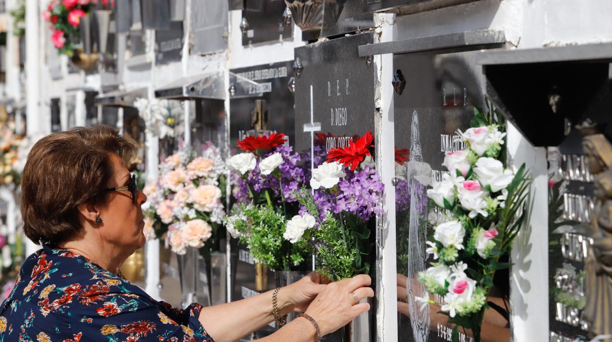 Una mujer coloca flores en el cementerio de San Rafael