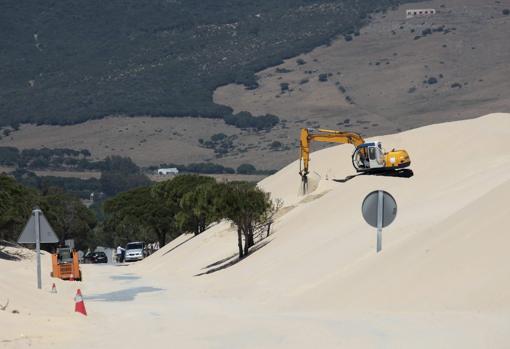 Una máquina mueve arena de la duna de la playa de Valdevaqueros