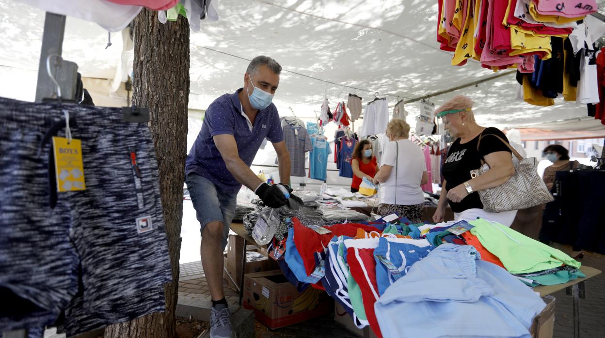 Un vendedor de La Ladera higieniza la ropa del puesto con un spay