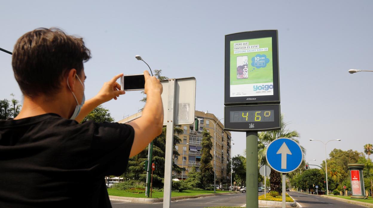 Un joven fotografía con su móvil un termómetro urbano en Córdoba