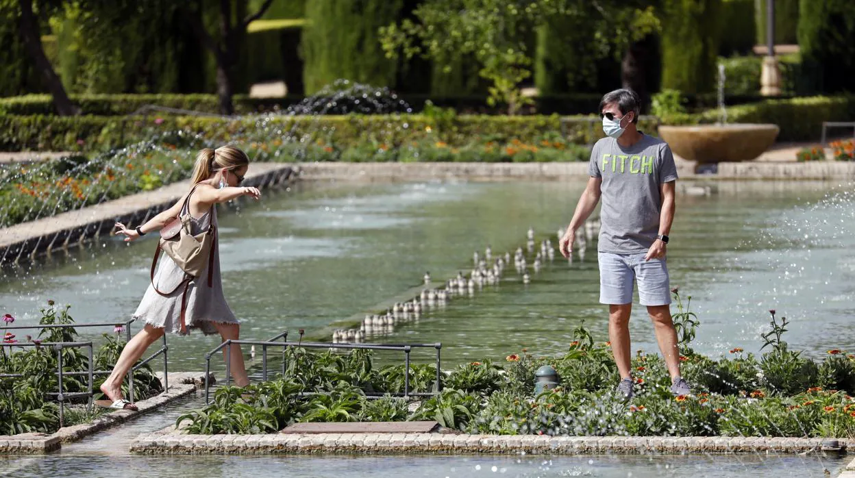 Dos turistas paseon entre los surtidores de agua de los Jardines del Alcázar de Córdoba