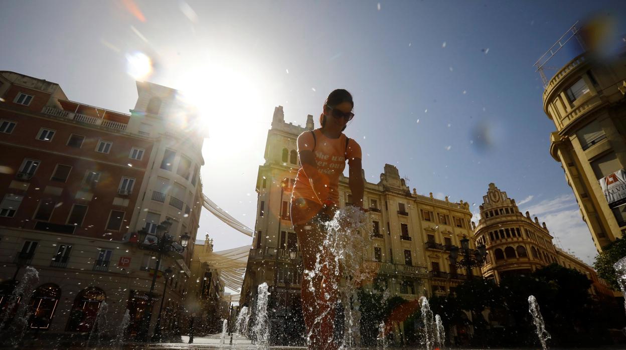 Una joven juega con los caños de agua de la plaza de las Tendillas