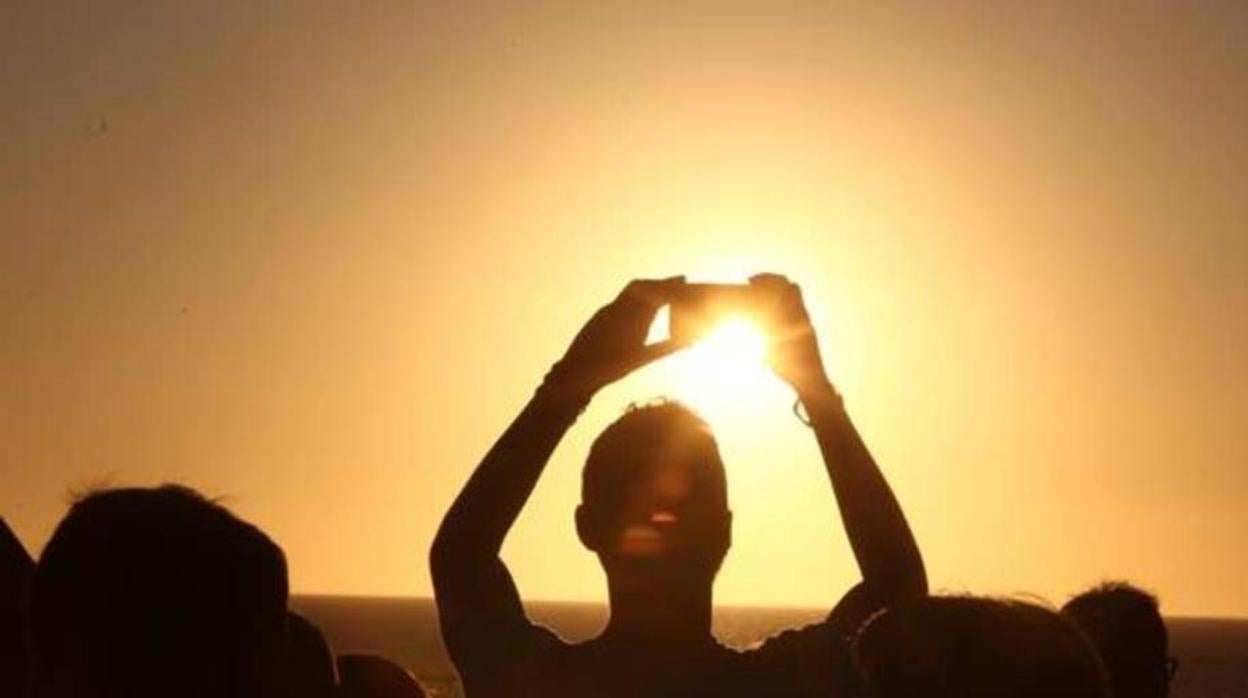 Un veraneante toma fotos de una puesta de sol en Cádiz