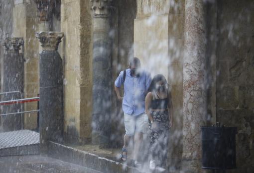 Dos personas se refugian del agua en el Patio de los Naranjos