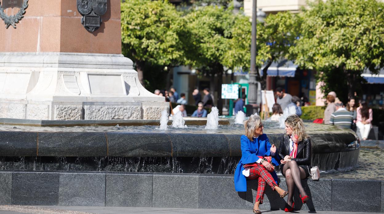 Dos personas hablan en la fuente de la plaza de las Tendillas