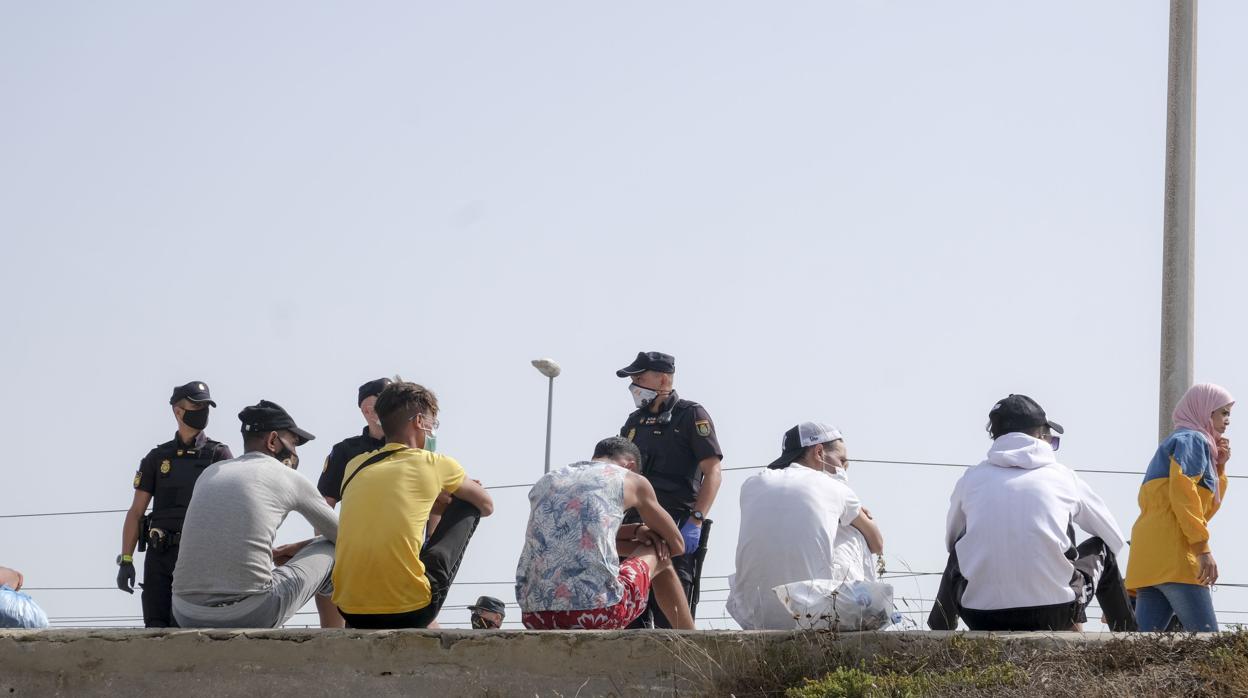 Inmigrantes recién llegados a Andalucía, custodiados por agentes de la Policía Nacional en la playa de Cortadura, en Cádiz capital