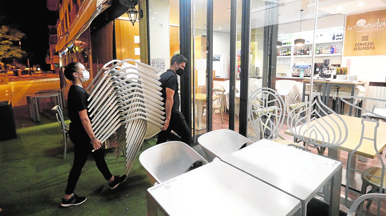 Trabajadores de «La Siesta», en María la Judía, recogen la terraza en la noche del lunes