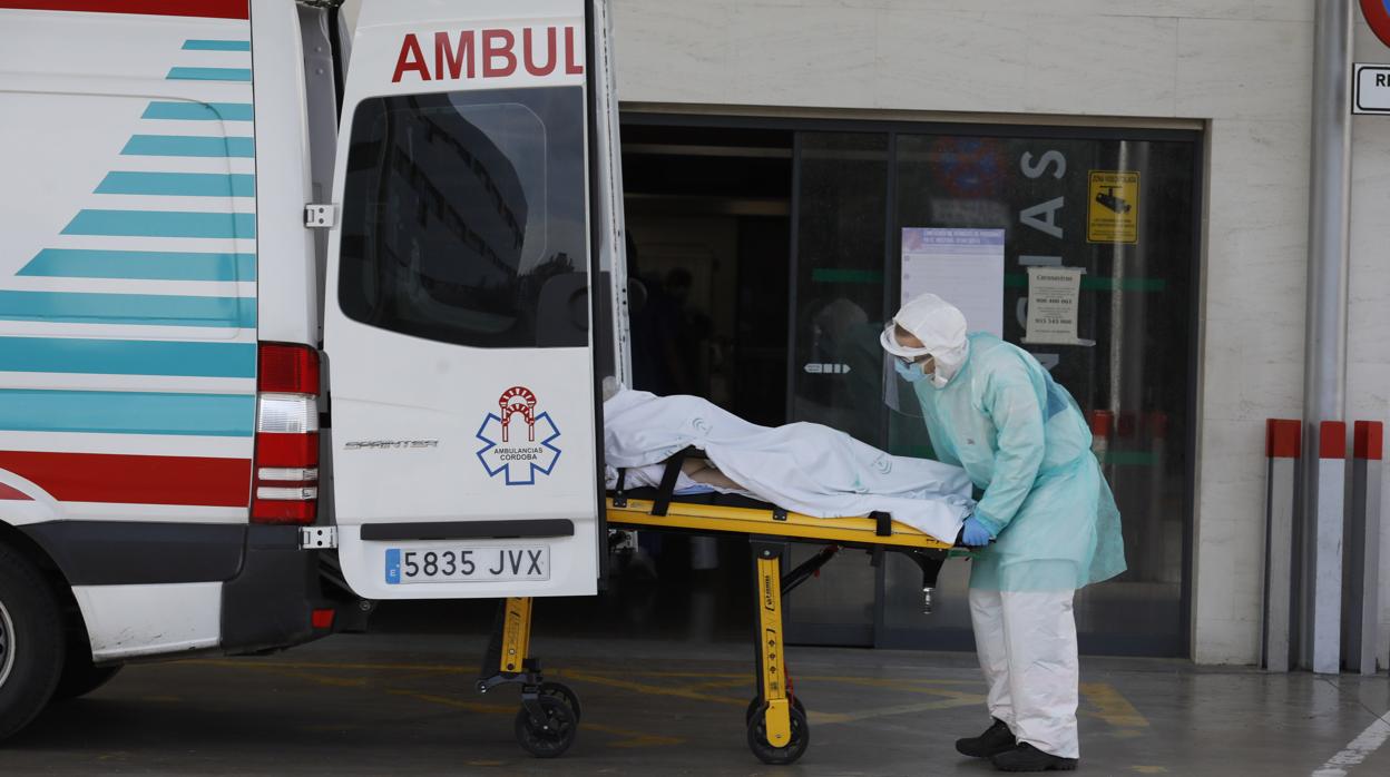 Una sanitaria sube a un enfermo a la ambulancia en la puerta de Urgencias del Reina Sofía