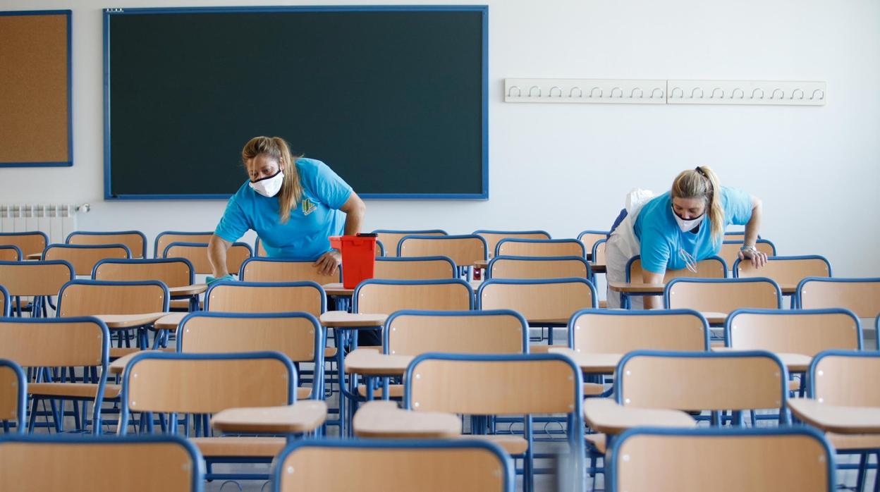 Trabajadoras de Sadeco desinfectan las sillas de un aula en el colegio Turruñuelos