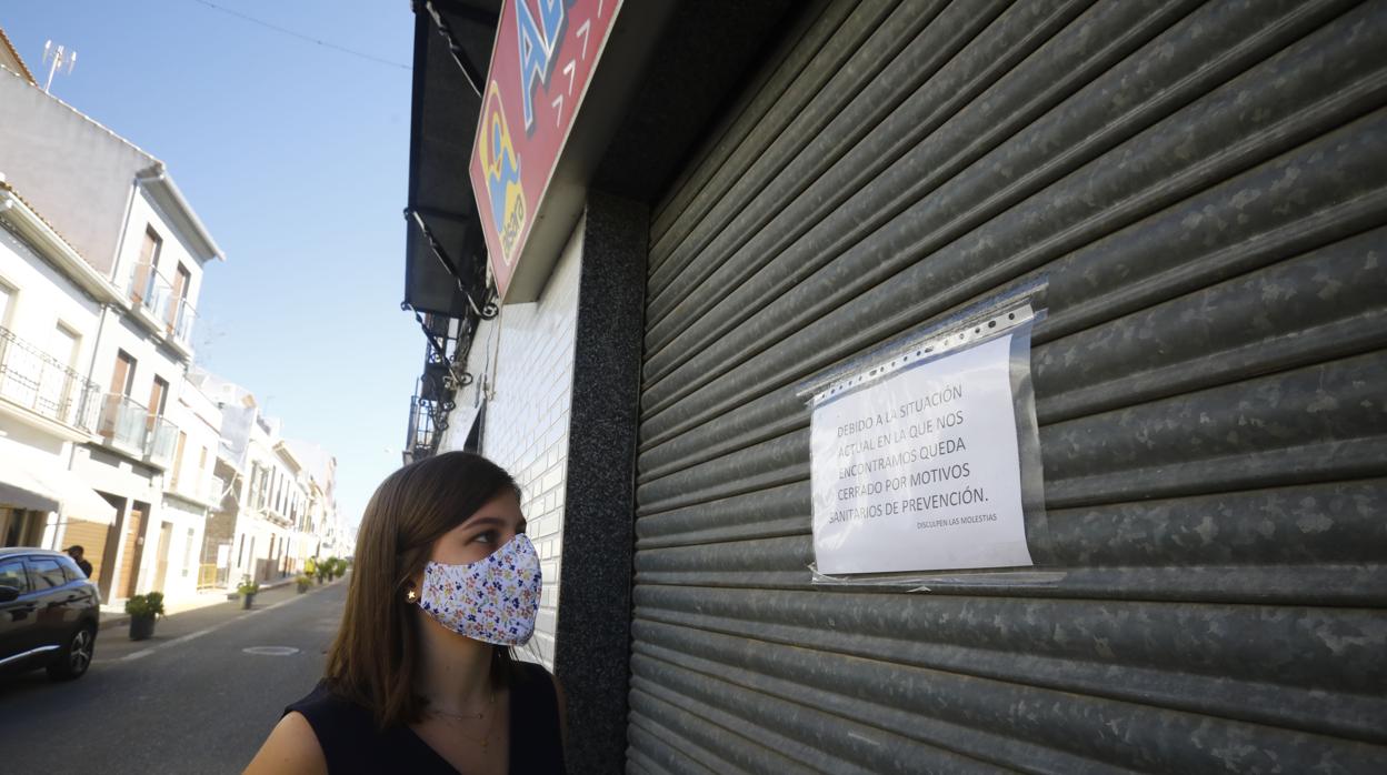 Una joven observa el cartel de un establecimiento cerrado en Montalbán