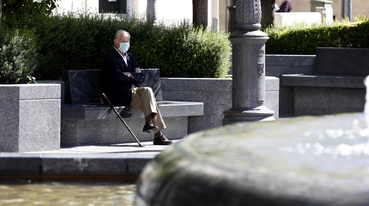 Un hombre mayor, con mascarilla y bastón en un banco de Las Tendillas