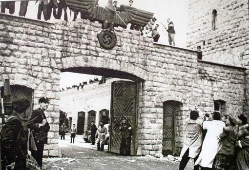 Icónica imagen del campo de Mathausen tras su liberación: un grupo de exiliados españoles derriba el águila nazi de la entrada. Juan cree ser el hombre con la gabardina blanca en la puerta