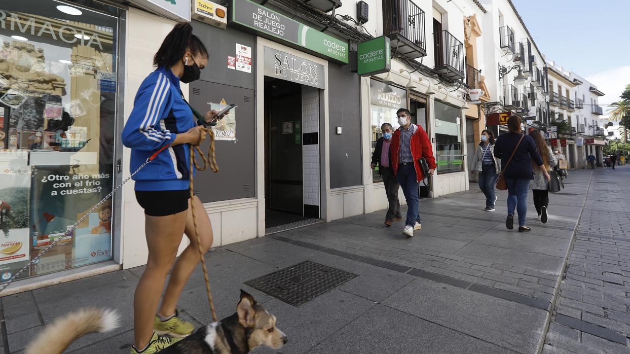 Una joven con sus mascotas junto a un salón de juego en el casco urbano