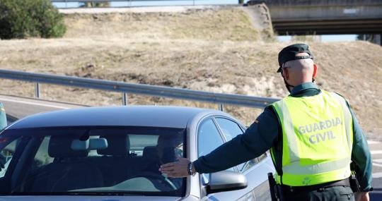 Un agente de la Guardia Civil deteniene a un turismo