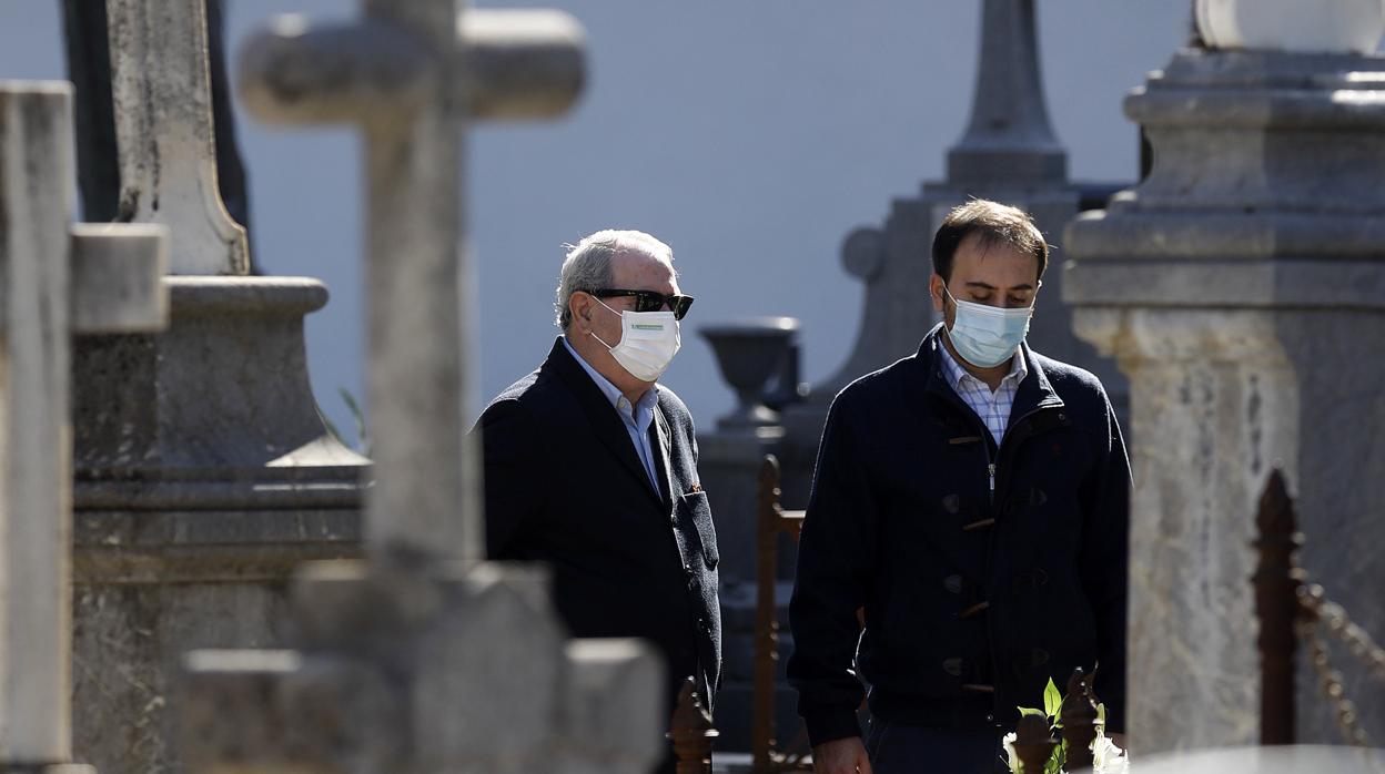 Dos personas delante de una tumba en el cementerio de la Salud