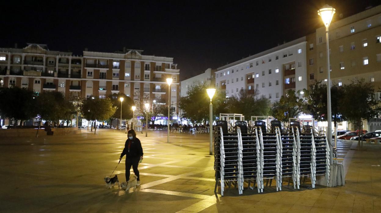 Una mujer pasea a su perro mientras las sillas y mesas de los bares de una plaza de Córdoba están recogidas por las medidas restrictivas