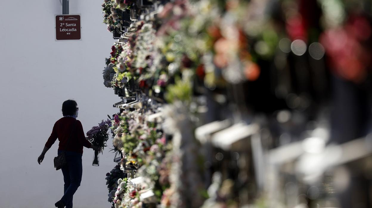 Una persona, con un ramo de flores en el cementerio