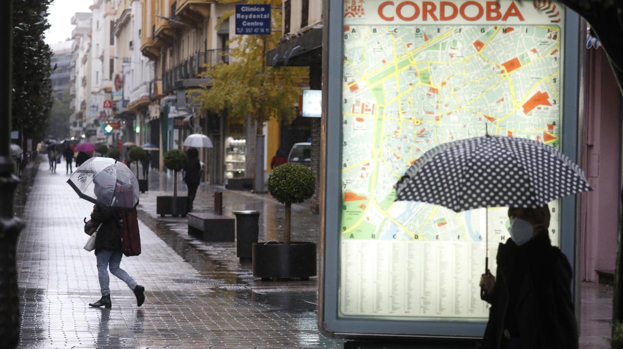 Varias personas pasean bajo la lluvia en Cruz Conde