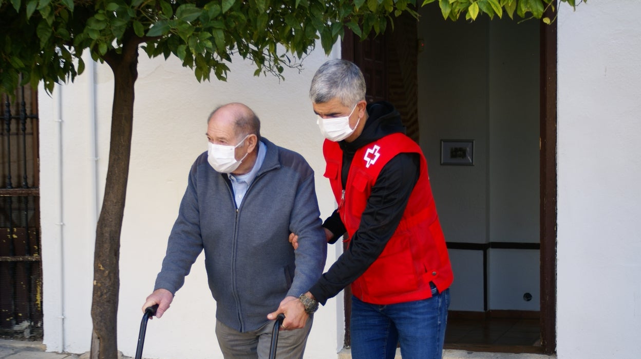 Un voluntario de Cruz Roja acompaña a una persona mayor