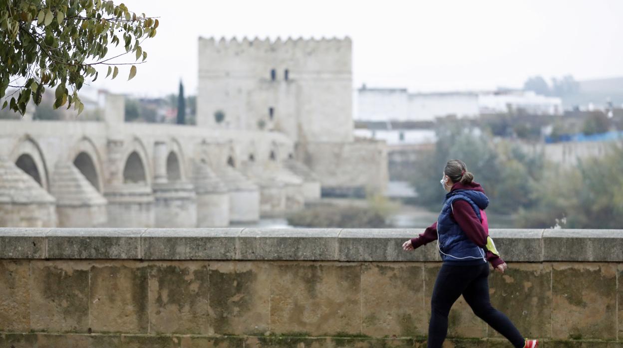 Una mujer hace deporte junto al Puente Romano de Córdoba