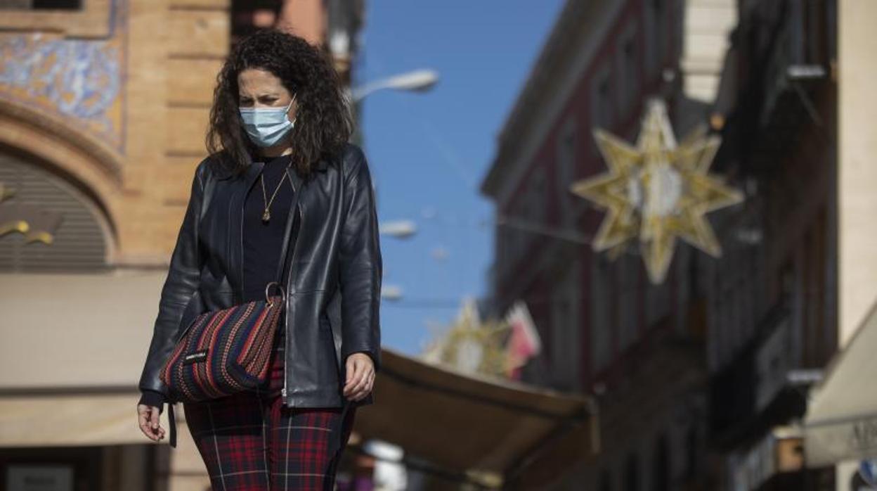 Una señora pasea con la mascarilla junto a las luces navideñas