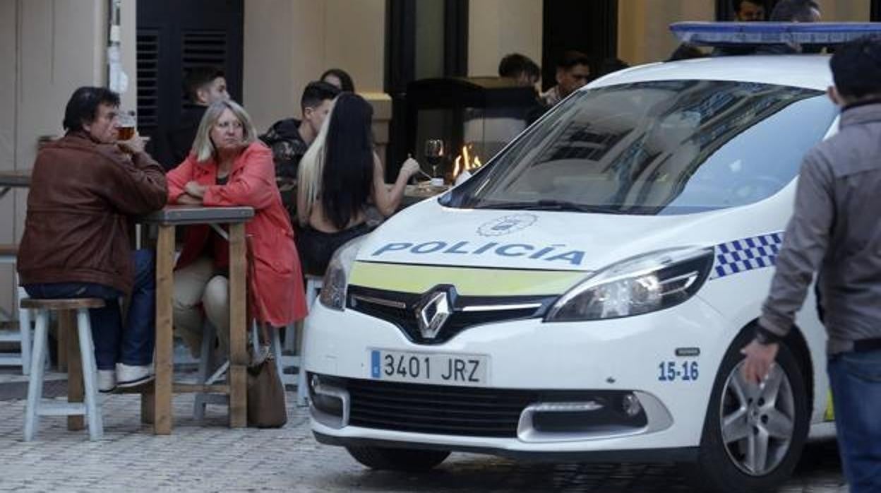 Una patrulla de la Policía pasa junto a una terraza