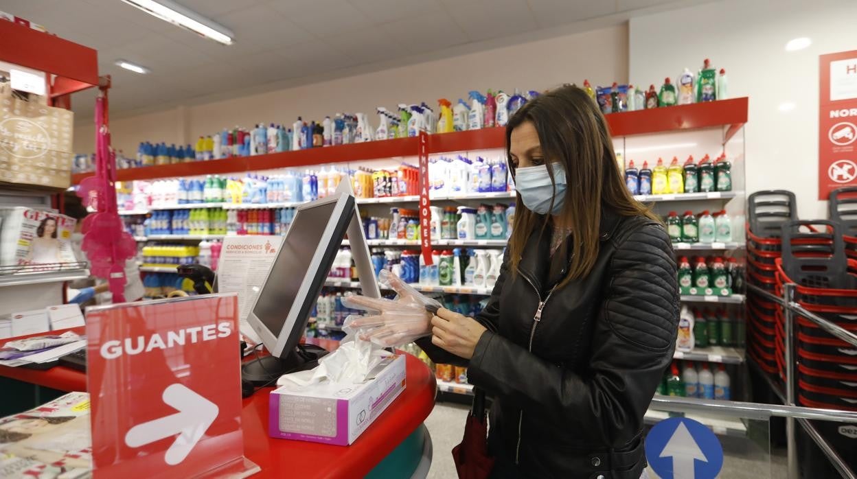 Una mujer se pone guantes en un supermercado Deza en Córdoba