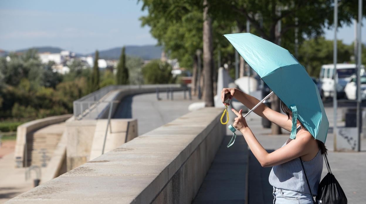 Una mujer con un parasol hace una foto cerca del río Guadalquivir