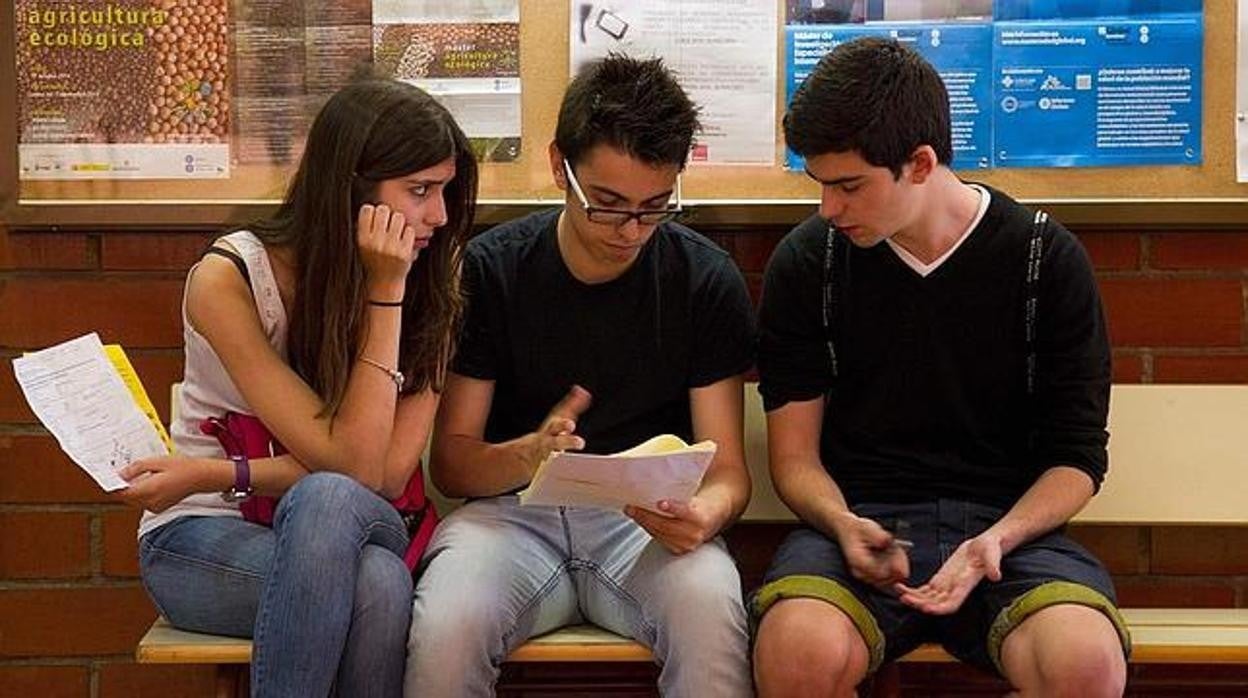 Tres estudiantes conversan en el pasillo de su centro