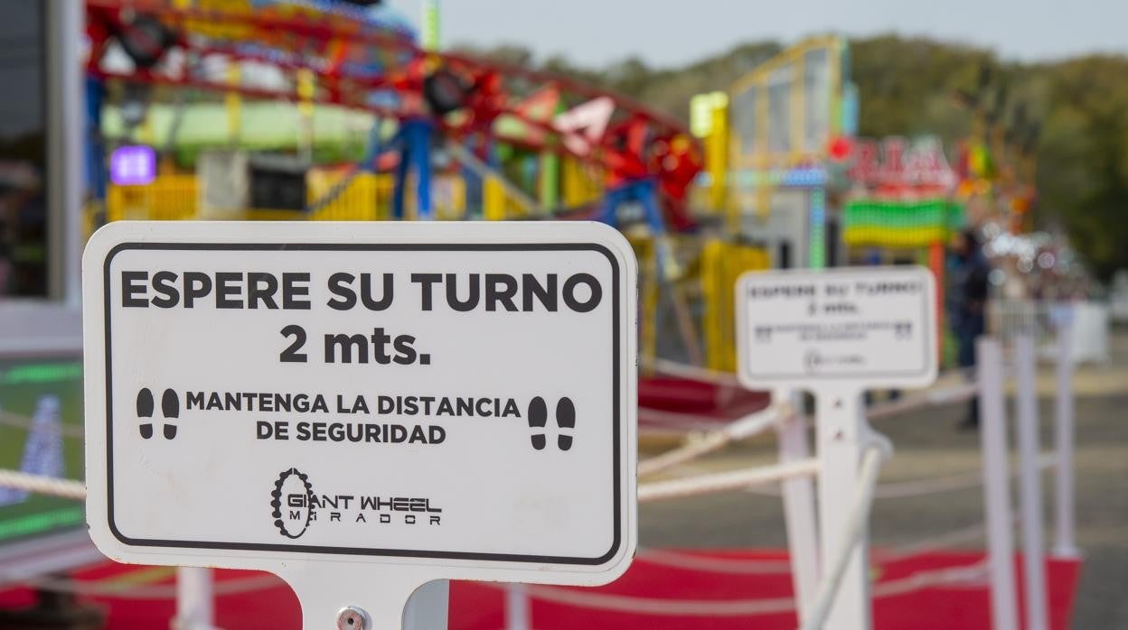 Montaje de atracciones de feria con carteles de las medidas de seguridad