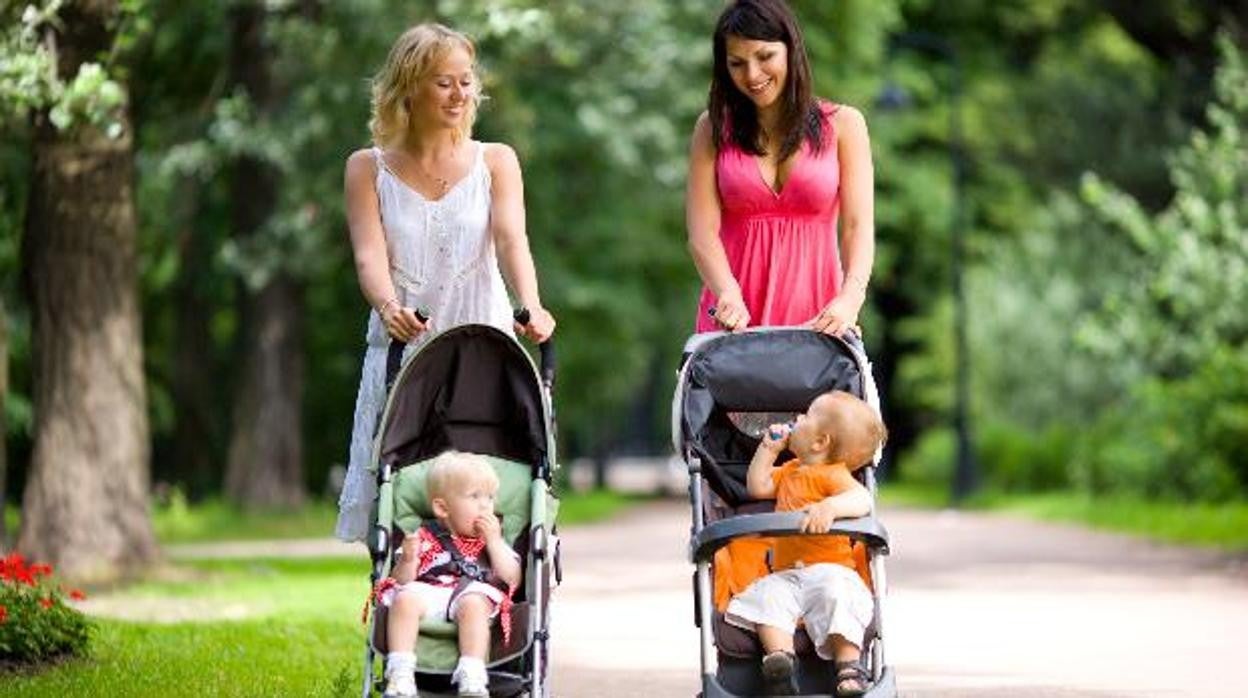 Bebés de paseo por un parque con sus madres