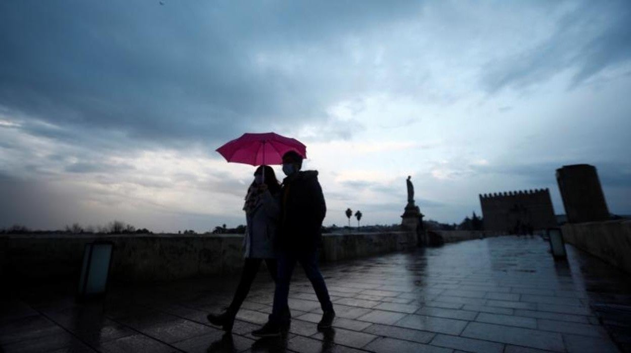 Una pareja pasea por el Puente Romano en un día de lluvia