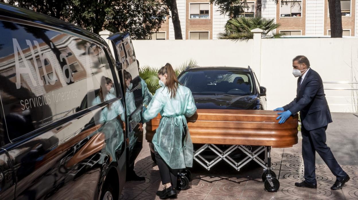 Operarios de una funeraria sacan un féretro con un fallecido a causa de Covid-19